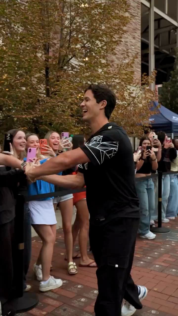 Students crowding a barrier to greet a guest at an outdoor event in Boulder