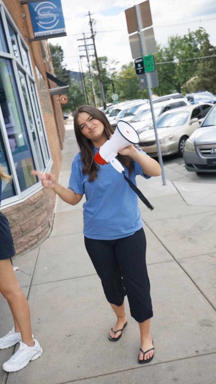 A woman with a megaphone at a sidewalk pop-up tent